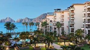 Un resort con edificios de varios pisos, piscina y palmeras.