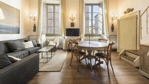 Une pièce comprenant un canapé, une table à manger, des chaises et un téléviseur.