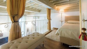 Une chambre à coucher avec un lit, un banc et un balcon agrémenté de rideaux.