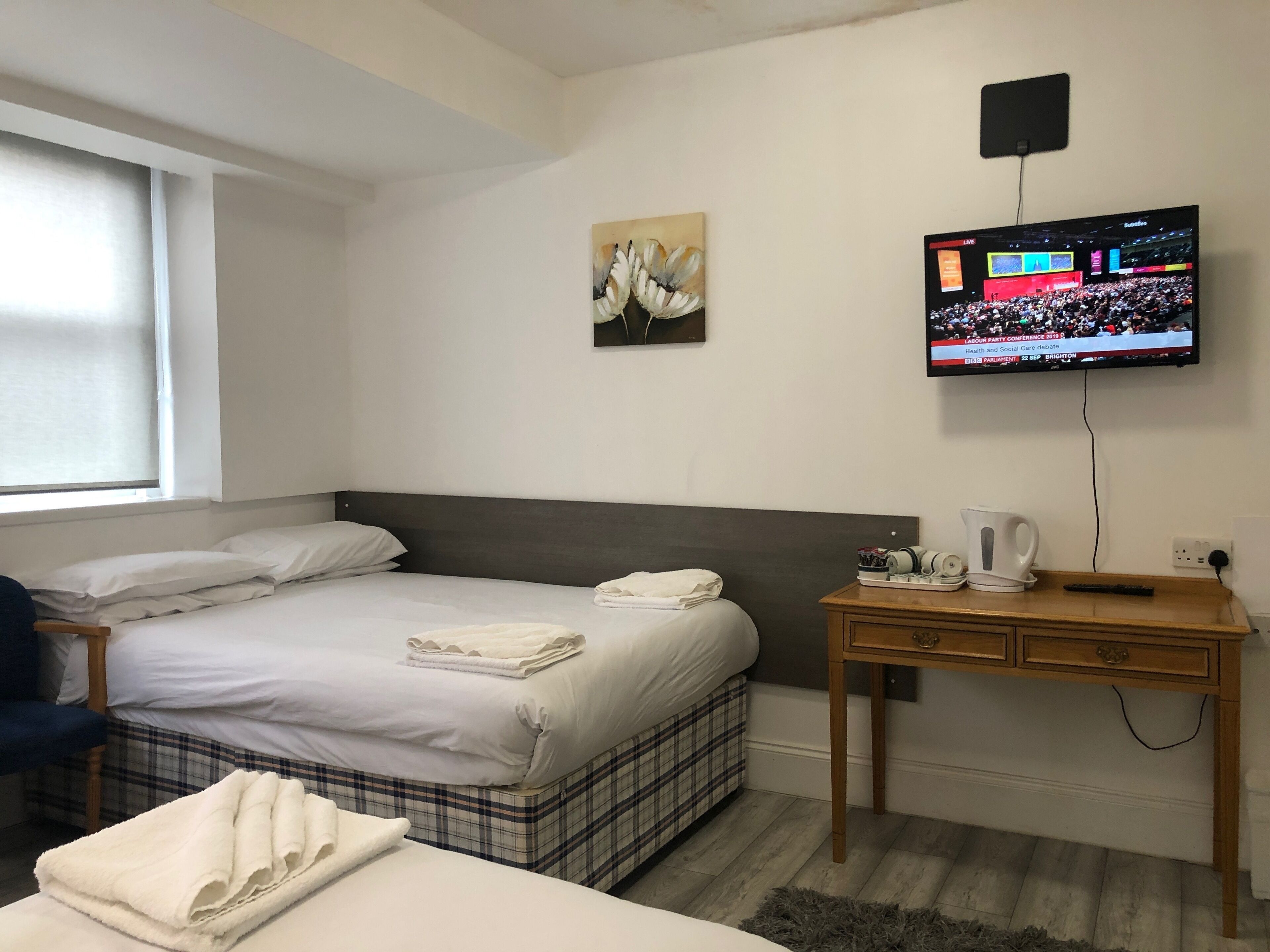 A hotel room with a bed, a desk, a television, and a window.