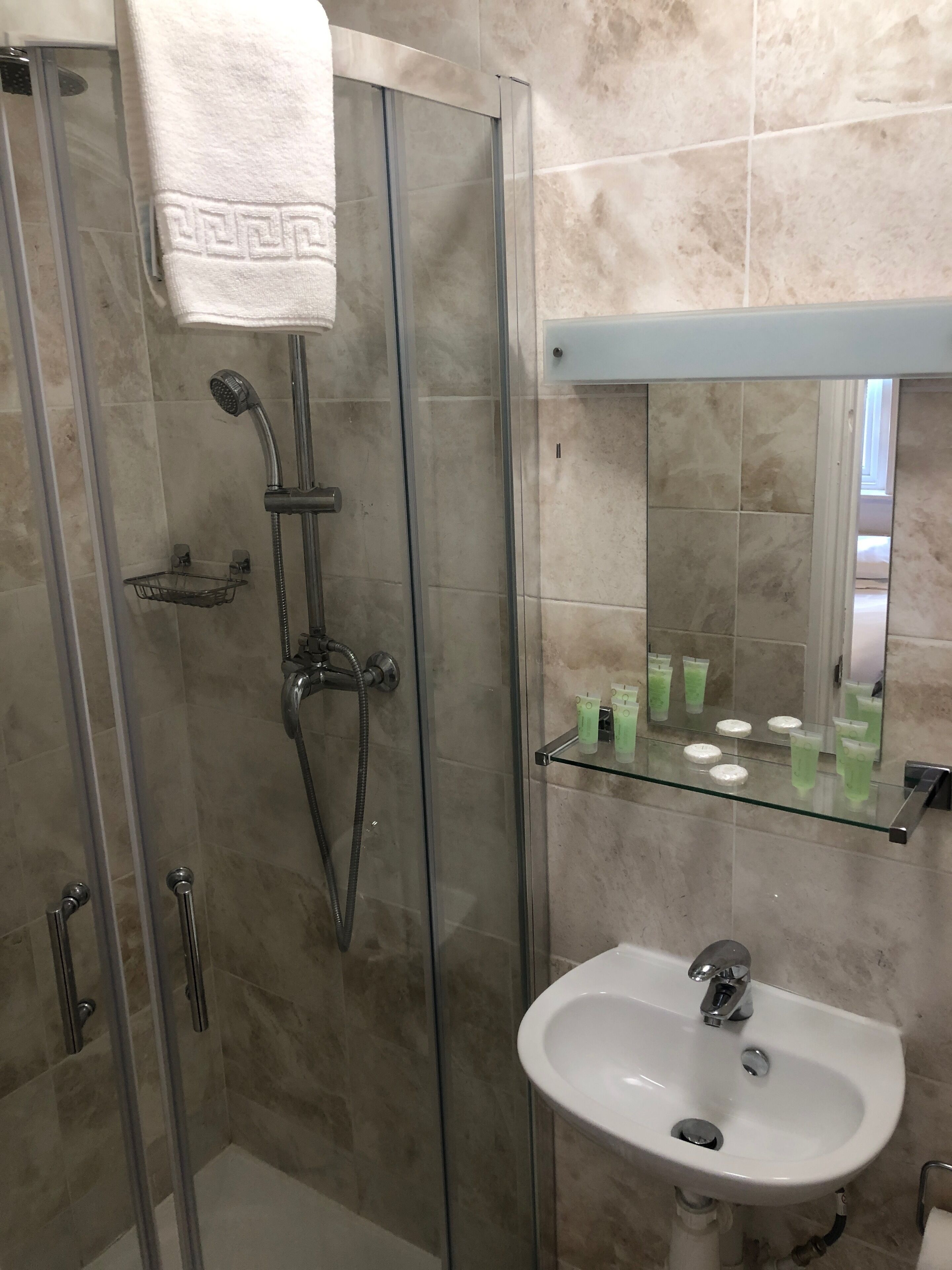 Ein modernes Badezimmer mit einer gläsernen Dusche, einem weißen Waschbecken und einem Spiegel darüber.