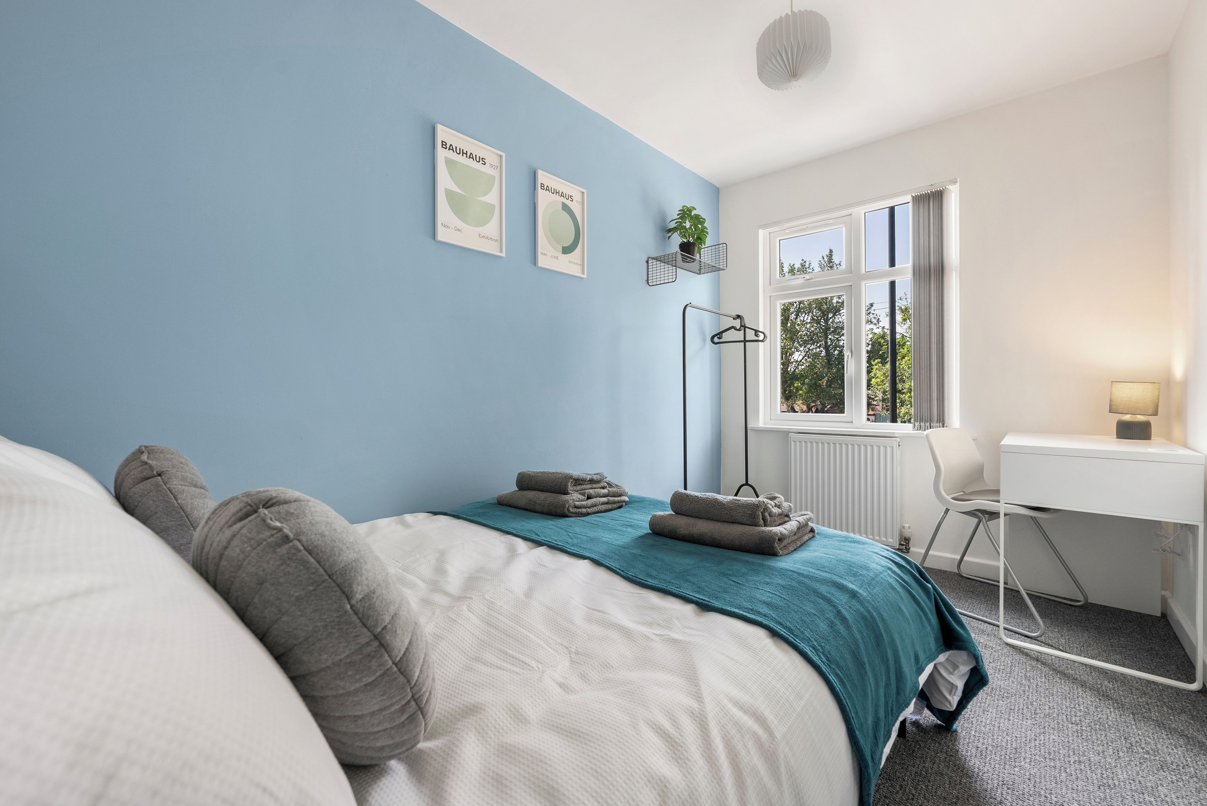 A bedroom with a bed, a desk, and a window.