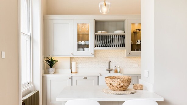 A modern kitchen with white cabinetry, a central island with a woven basket, and two white bar stools. - Stylish 2Bed in Leamington Spa with Parking - Pass The Keys (Leamington Spa)