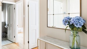 A hallway with a marble-topped console table, a large mirror, and a vase with blue flowers. - Stylish 2Bed in Leamington Spa with Parking - Pass The Keys (Leamington Spa)