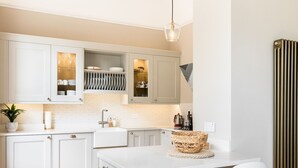 A modern kitchen with white cabinetry, a central island with two chairs, and a hanging light fixture. - Stylish 2Bed in Leamington Spa with Parking - Pass The Keys (Leamington Spa)