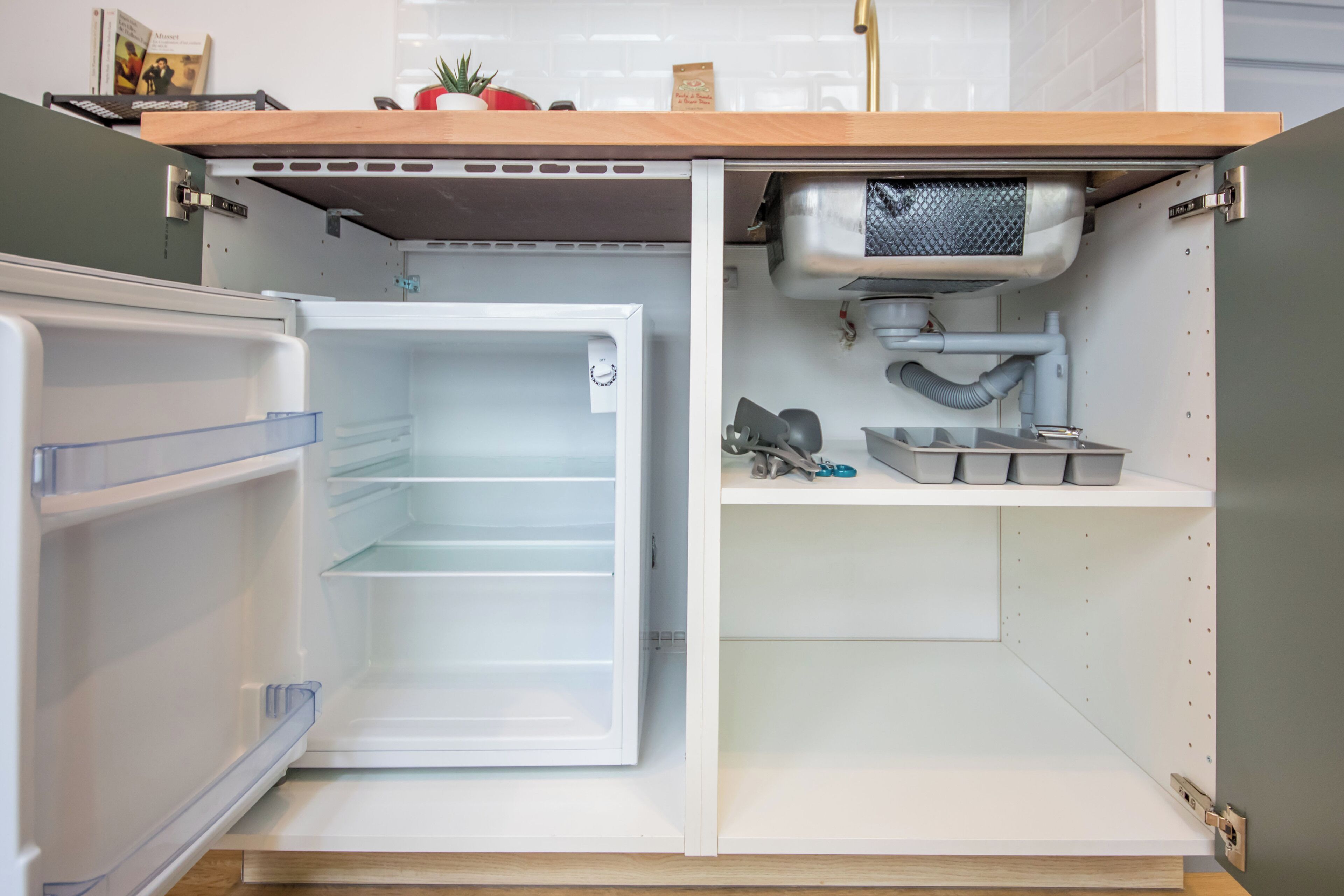 Un refrigerador abierto con un estante de madera arriba y un interior blanco.