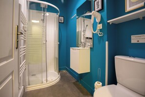 A bathroom with a glass-enclosed shower, a white toilet, and a sink with a mirror above it. - WS Opéra-Folies Bergères (Paris)