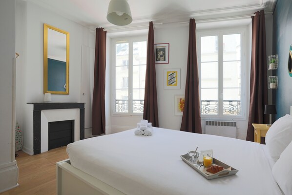 A hotel room with a bed, a fireplace, a window with curtains, and a tray with breakfast items. - WS Montorgueil-Louvre (Paris)