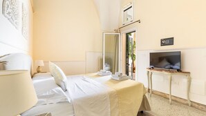 A hotel room with a bed, a TV on a small table, a mirror, and a window with a view.