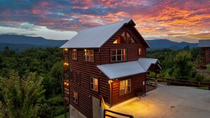 Eine Holzhütte mit vielen Fenstern, einer Veranda und Blick auf den umliegenden Wald und die Berge.