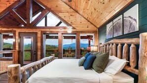 Eine Holzhütte mit Bett, großen Fenstern und Bildern an der Wand.