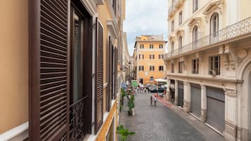 Une ruelle étroite pavée, bordée de bâtiments historiques dotés de balcons et de volets.