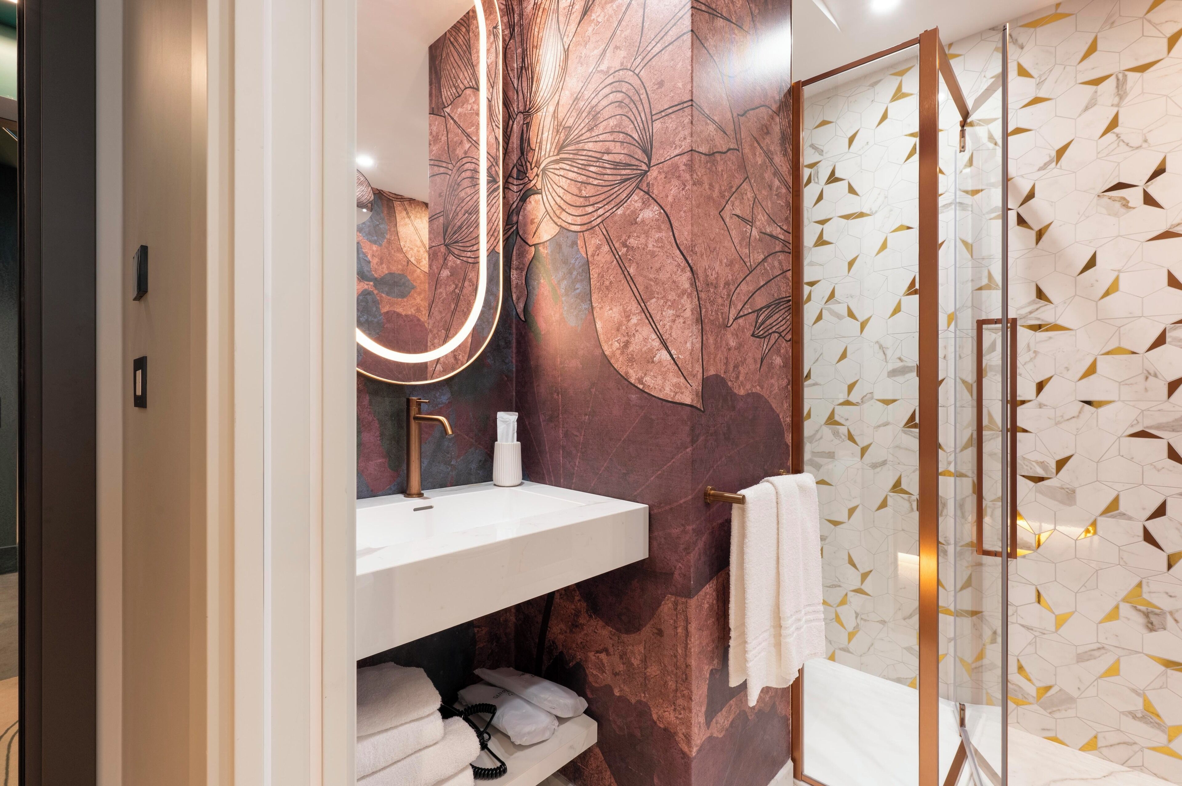 A modern bathroom with a marble sink, a large mirror, and a glass shower enclosure.