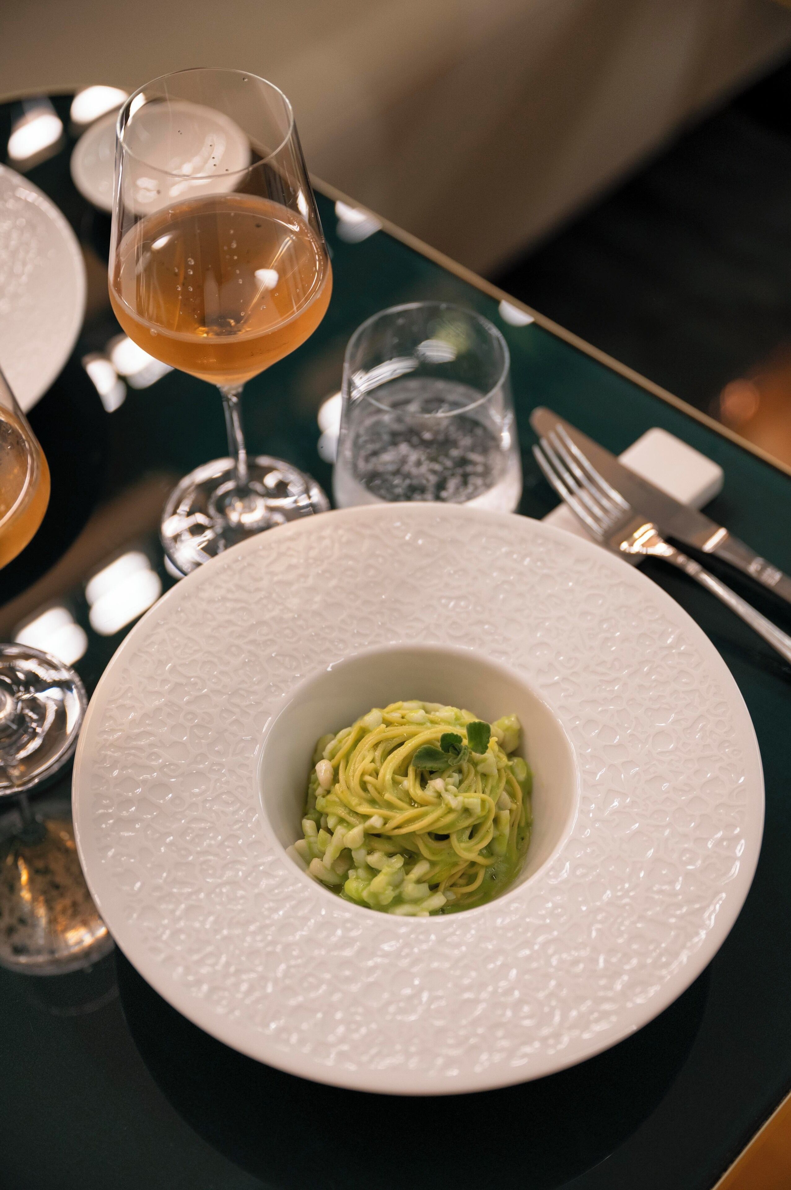 A plate of pasta with a glass of wine on a table.