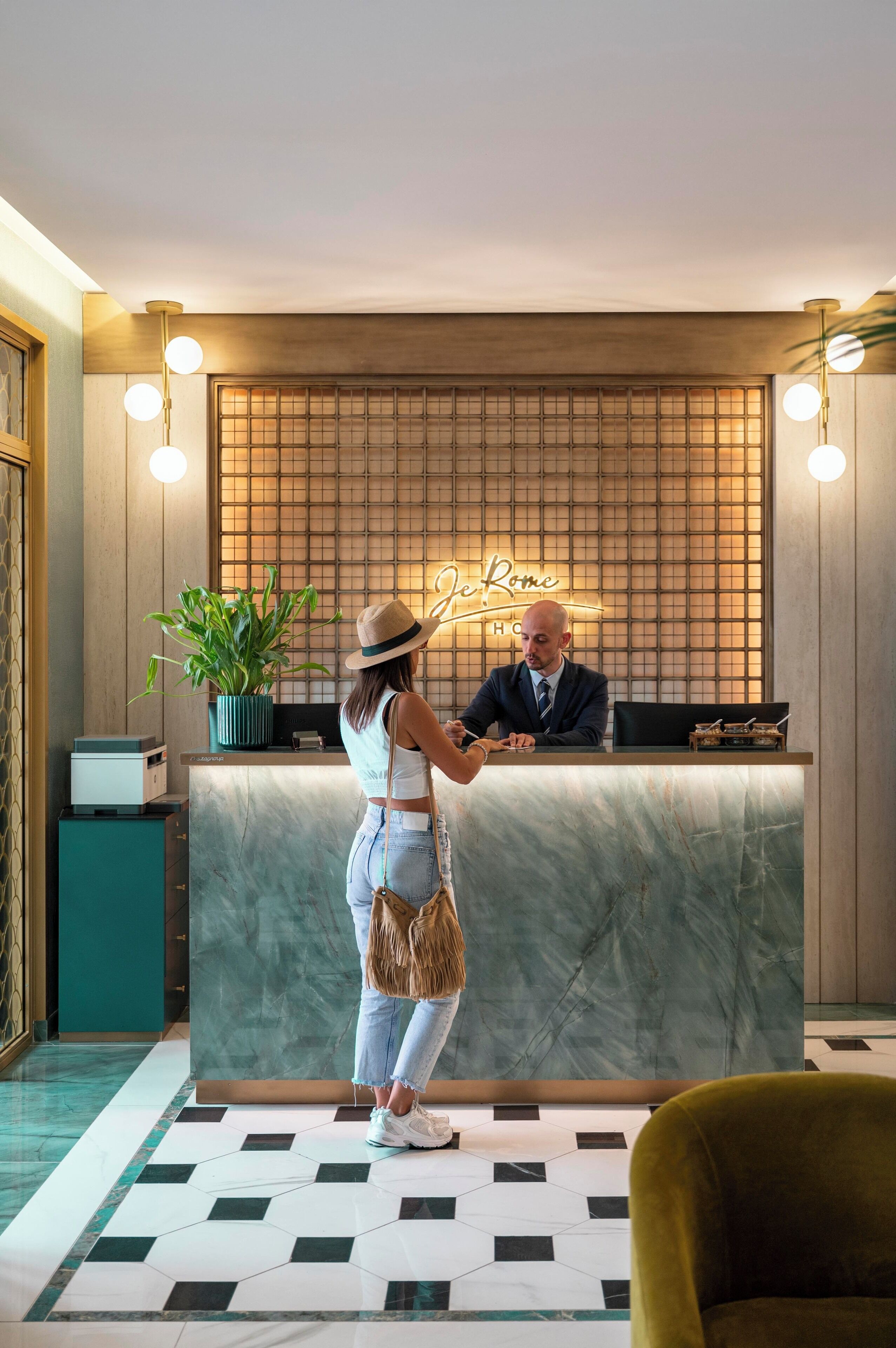A reception desk with a neon sign reading "De Rome Hotel," a potted plant, and a check-in counter.