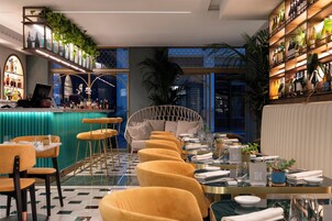 Un ristorante moderno con un'area bar, sedute con sedie gialle e un divano centrale.