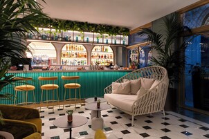 Zona bar con pavimento a scacchi, un divano e sgabelli da bar.