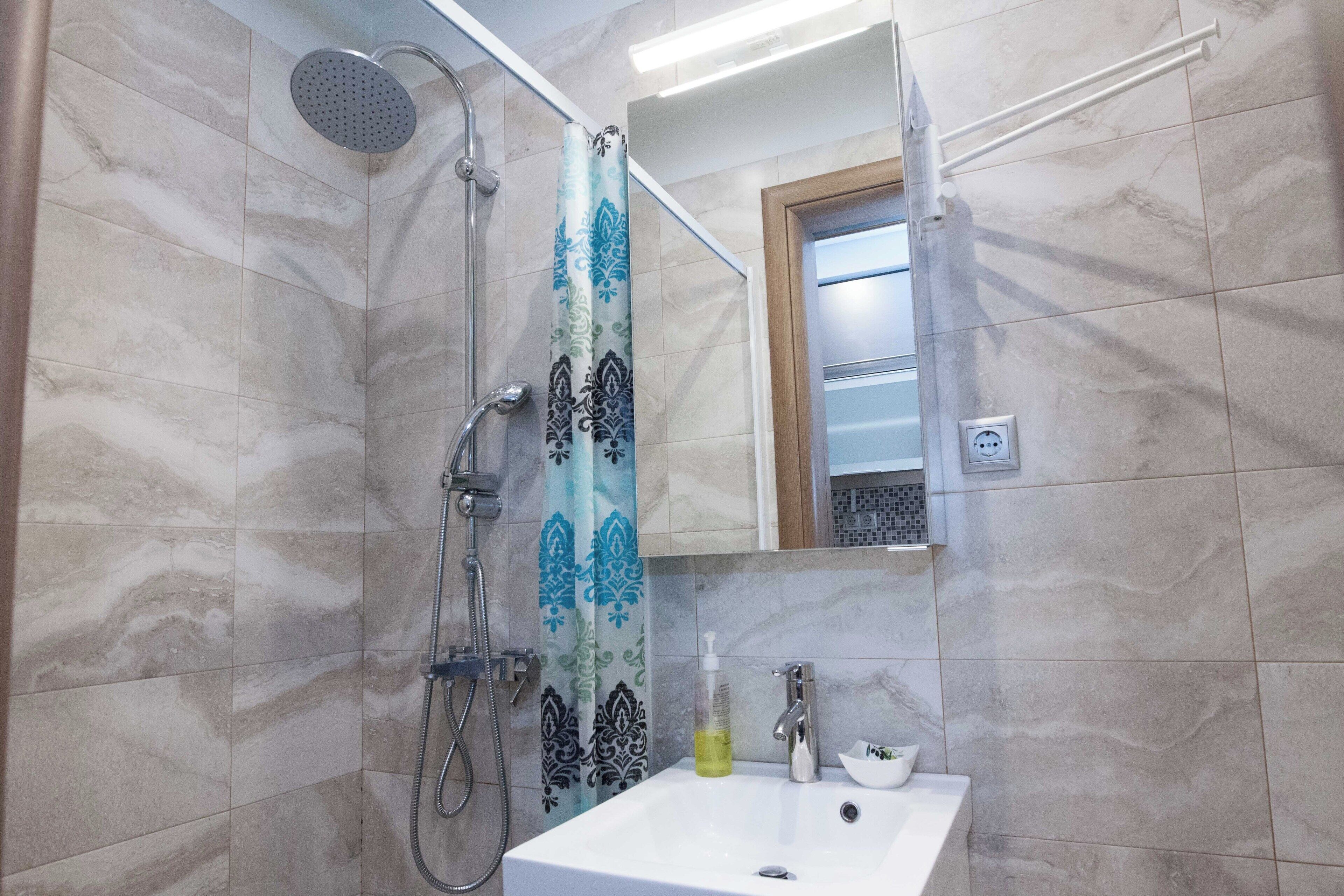 Un baño con ducha, lavabo y espejo.