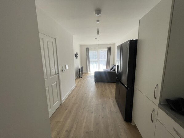 A modern kitchen with a built-in refrigerator, wooden flooring, and a sliding door leading to a balcony.