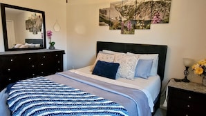 Un dormitorio con cama, cómoda, espejo y decoración en la pared.