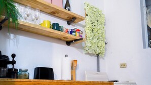 A kitchen with wooden shelves, a built-in oven, and a countertop with various kitchen items.