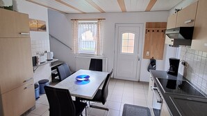 Kompakti keittiö, jossa on ruokapöytä, tuolit, mikroaaltouuni ja kahvinkeitin.