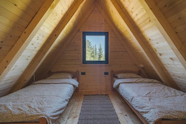 A small attic bedroom with two single beds, a window with a view of trees, and wooden beams. - Mountain homes Durmitor 2 (Zabljak)