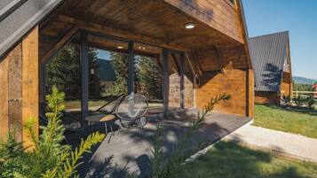 A modern wooden house with a covered patio area featuring a table and chairs.