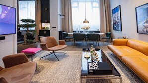 A modern living room with a sofa, armchairs, a coffee table, and a dining area with chairs and a table. - The Private Escape by Blue Medi Spa (Stockholm)