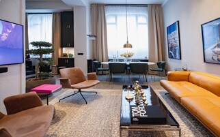 Una sala de estar moderna con un sofá, sillones, una mesa de centro y un comedor con sillas y una mesa.