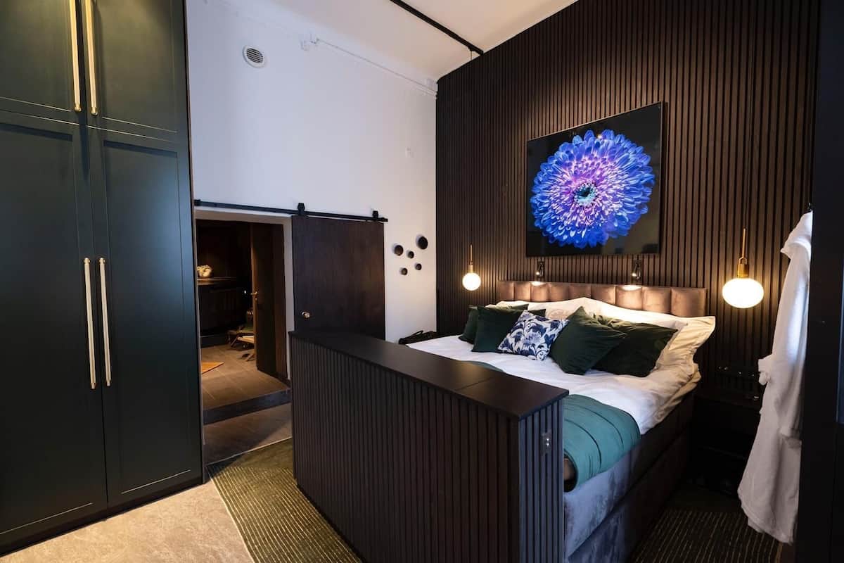 A modern bedroom with a bed, bedside tables, a large wall-mounted TV, and a wardrobe.