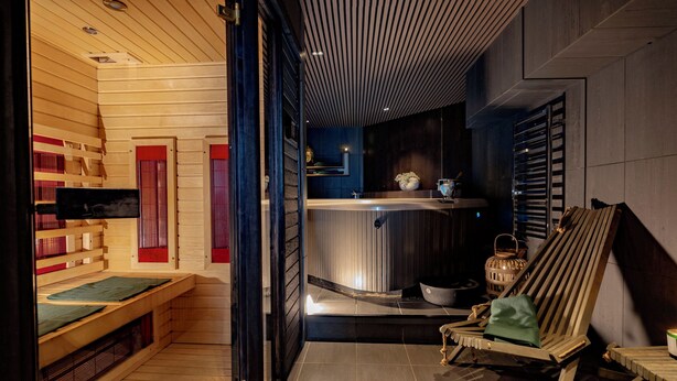 A sauna room with wooden benches, a massage table, and a steam room with a bench and a small table. - The Private Escape by Blue Medi Spa (Stockholm)