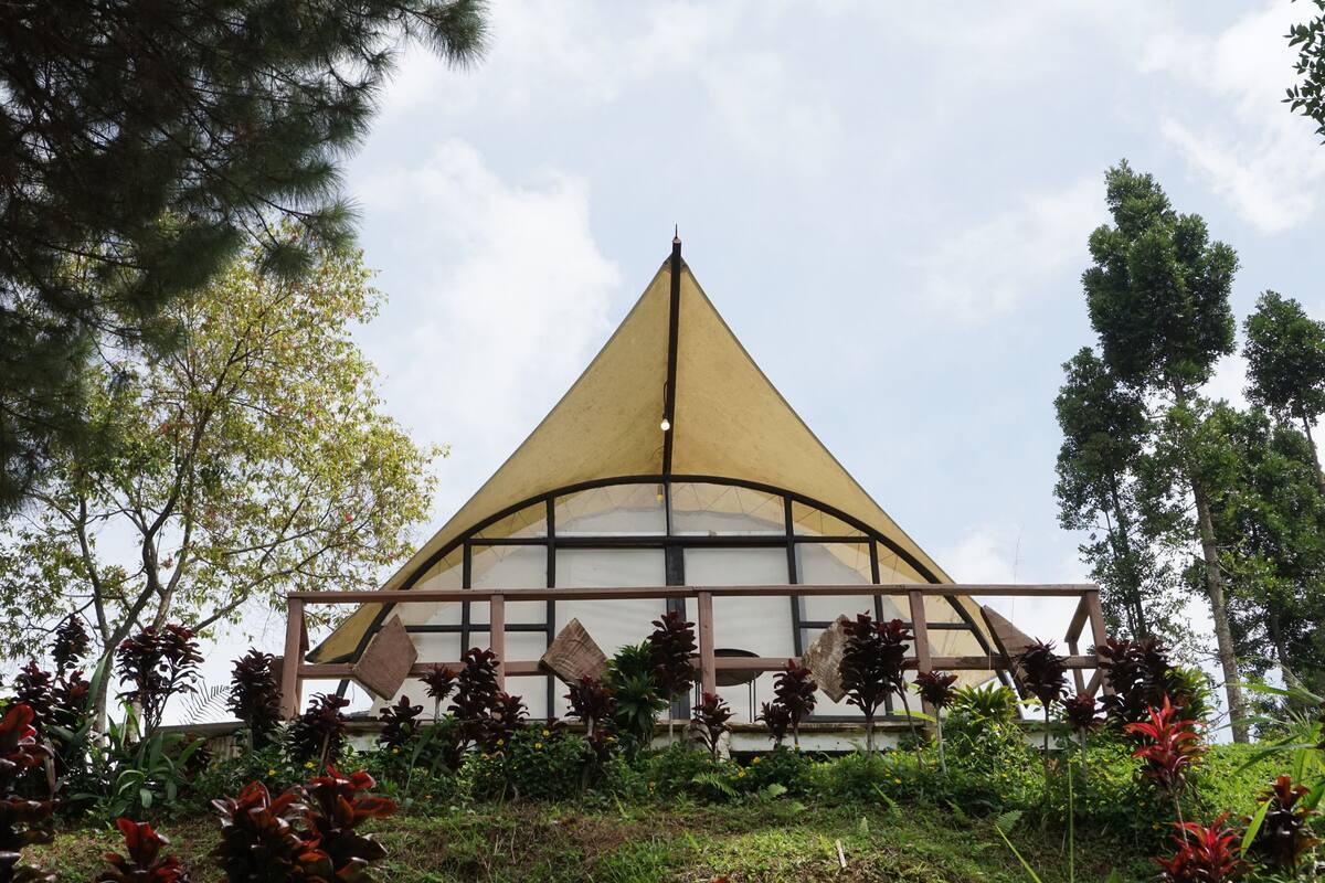A triangular building with a glass facade and a wooden structure in front.