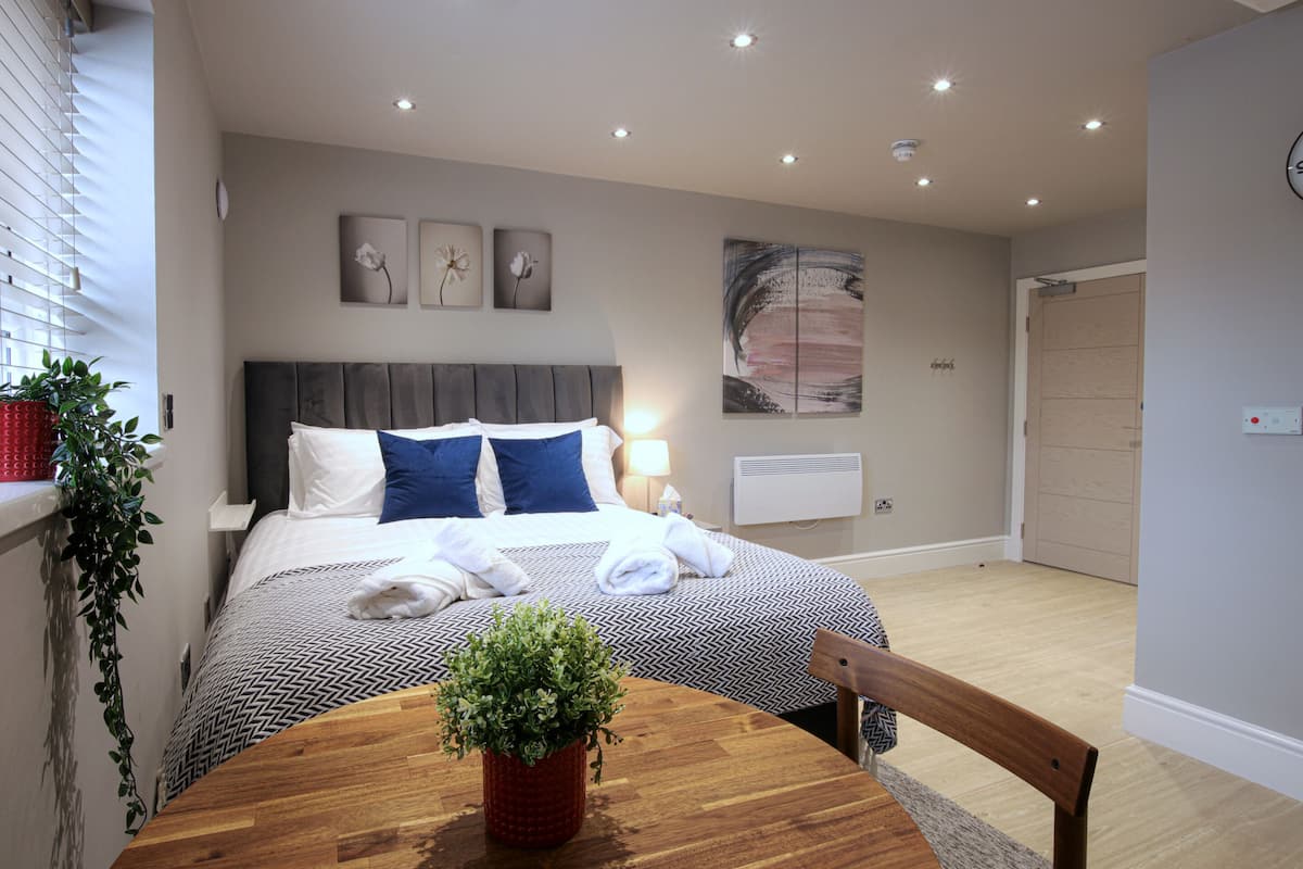 A bedroom with a bed, bedside table, and a potted plant.