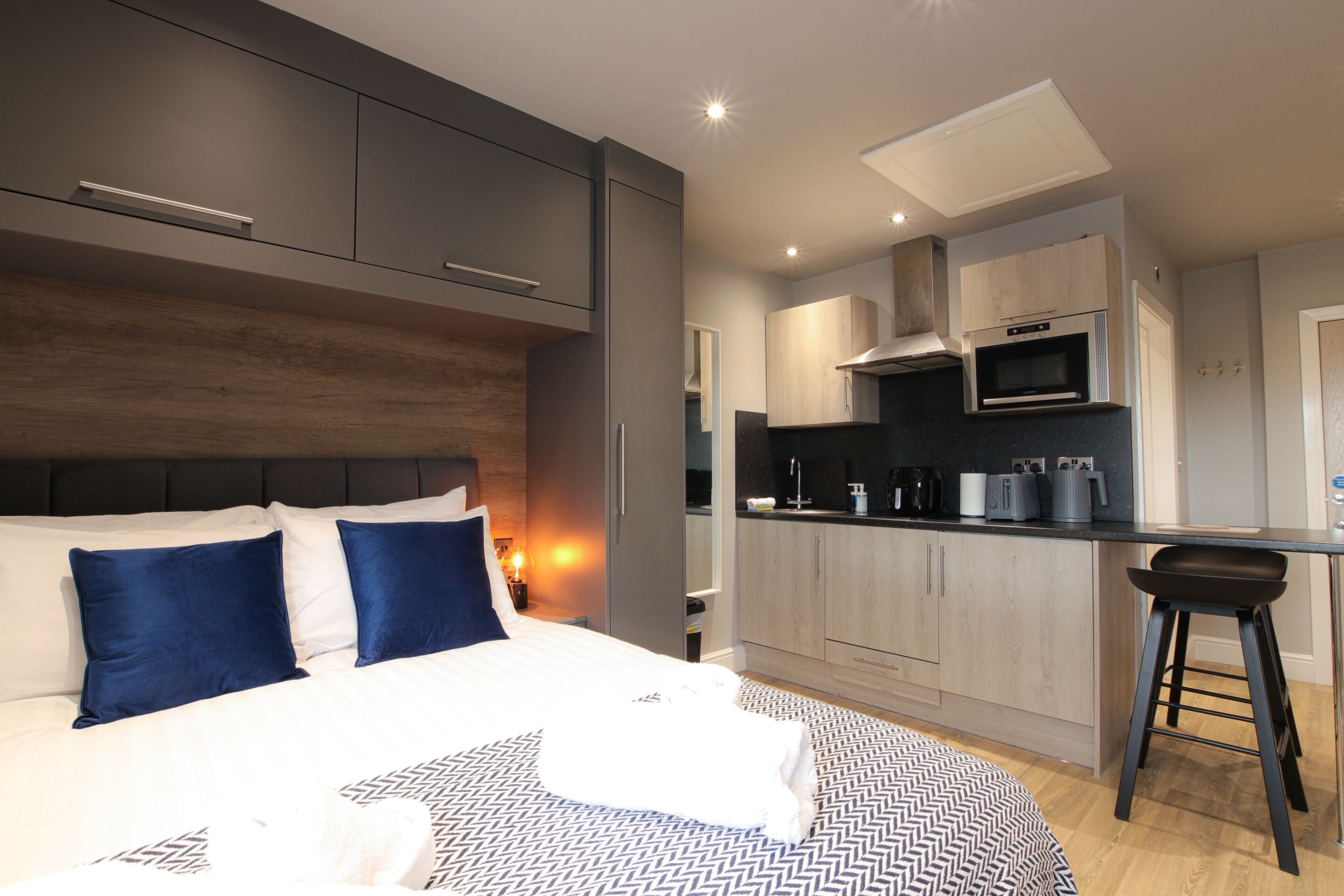 Ein modernes Hotelzimmer mit einem großen Bett, einer Küchenzeile und einer Bar.