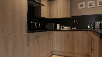 A modern kitchen with wooden cabinets, a black countertop, and a stainless steel range hood.