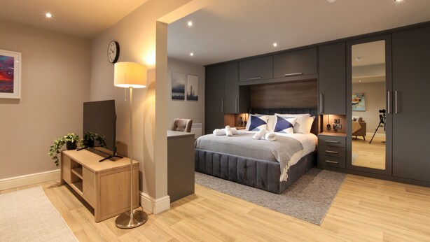 Une chambre moderne avec un grand lit, un bureau, un miroir et une armoire.