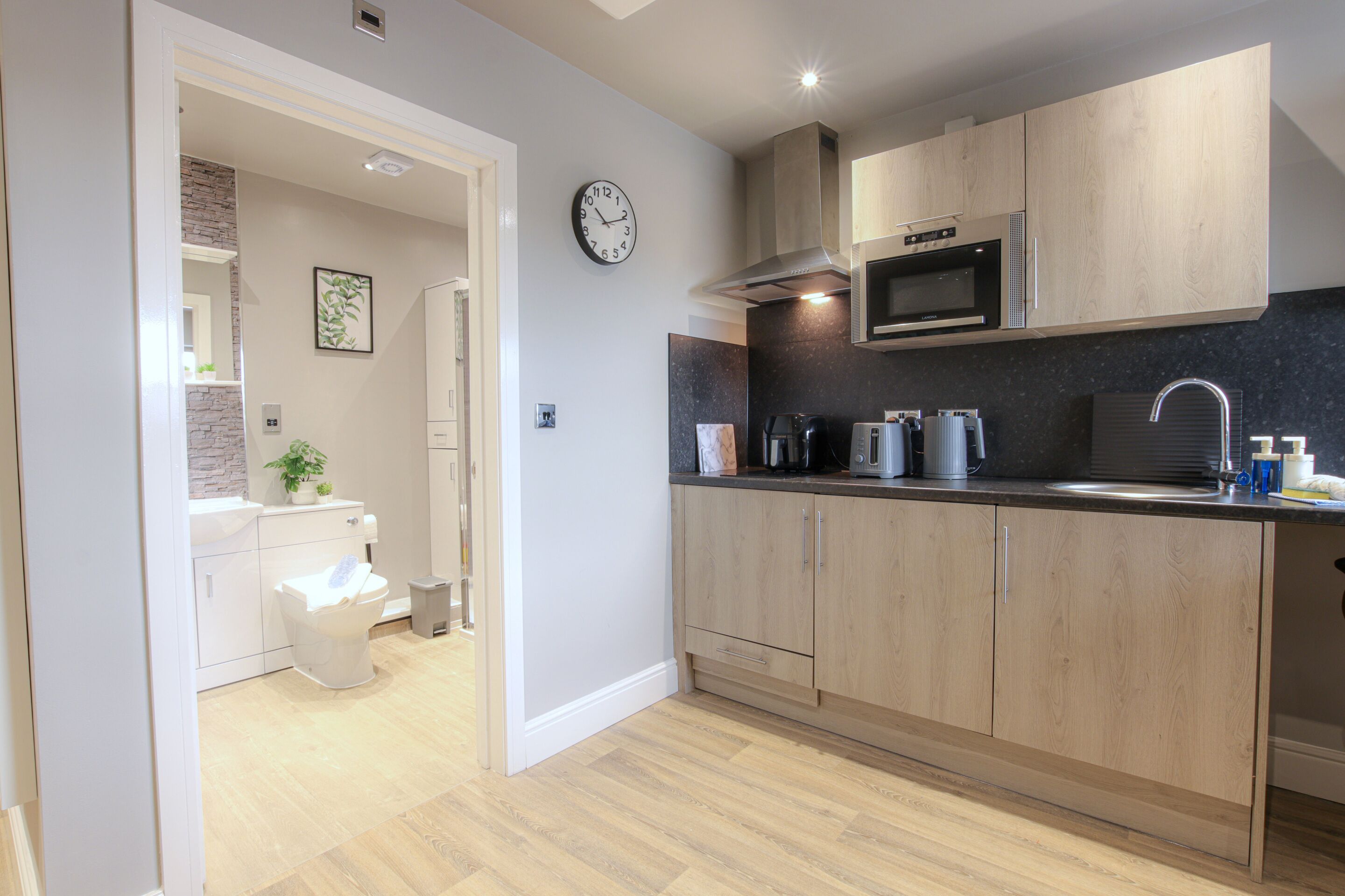 A modern kitchen with wooden cabinets, a microwave, and a sink.