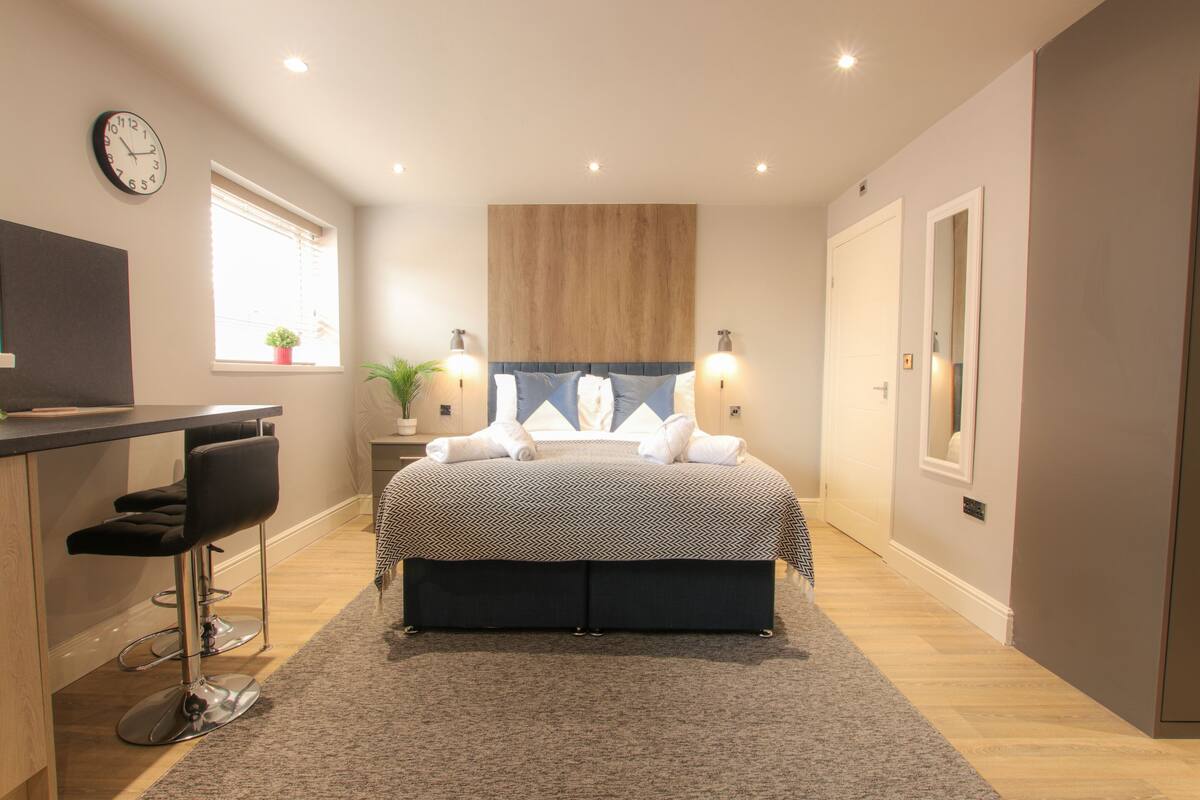 A modern bedroom with a bed, a desk, and a chair.