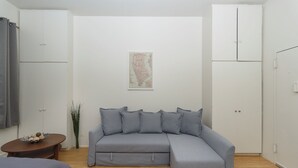 Un salon moderne avec un canapé d’angle gris, une petite table ronde et une carte accrochée au mur.