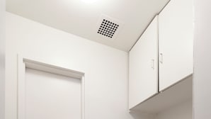 Une cuisine de taille réduite avec un fourneau blanc, un lave-vaisselle noir et une porte blanche.