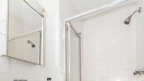 Une salle de bain avec une douche, un lavabo avec un miroir et un distributeur de savon.