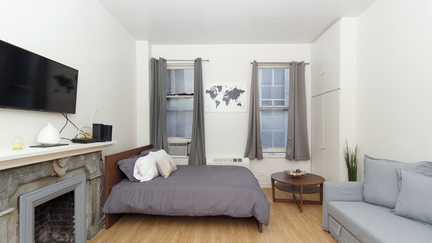 Une chambre moderne avec un lit, une télévision, une petite table, un canapé et une cheminée.