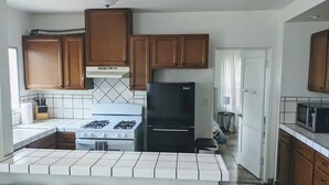 Una cocina con gabinetes de madera, estufa a gas, refrigerador negro y microondas.