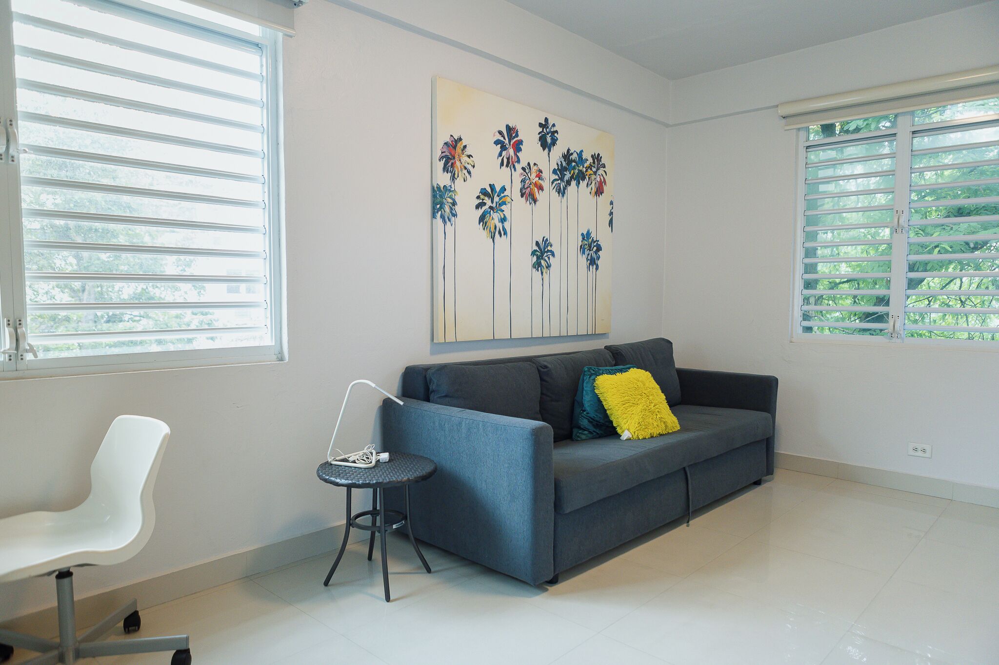 A modern living room with a grey sofa, a white chair, and a small round table.