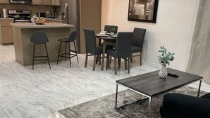 Una cocina moderna con una isla central, comedor con sillas y una mesa de centro.