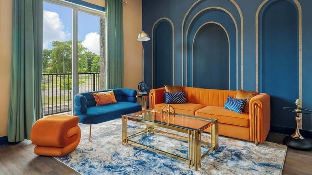 A living room with a blue sofa, an orange sofa, and a glass coffee table. - Chic Escape · 2mi to DT · Billiards · B-Nashy (Nashville)