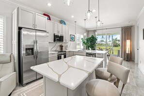 A modern kitchen with a central island, stainless steel appliances, and a view to the outdoors. - New 3-bed.2bath house in tranquil Fort Pierce. Walk to Beach and restaurants (Fort Pierce)