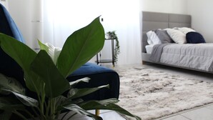 Une chambre à coucher avec un lit, une chaise bleue et une plante en pot.
