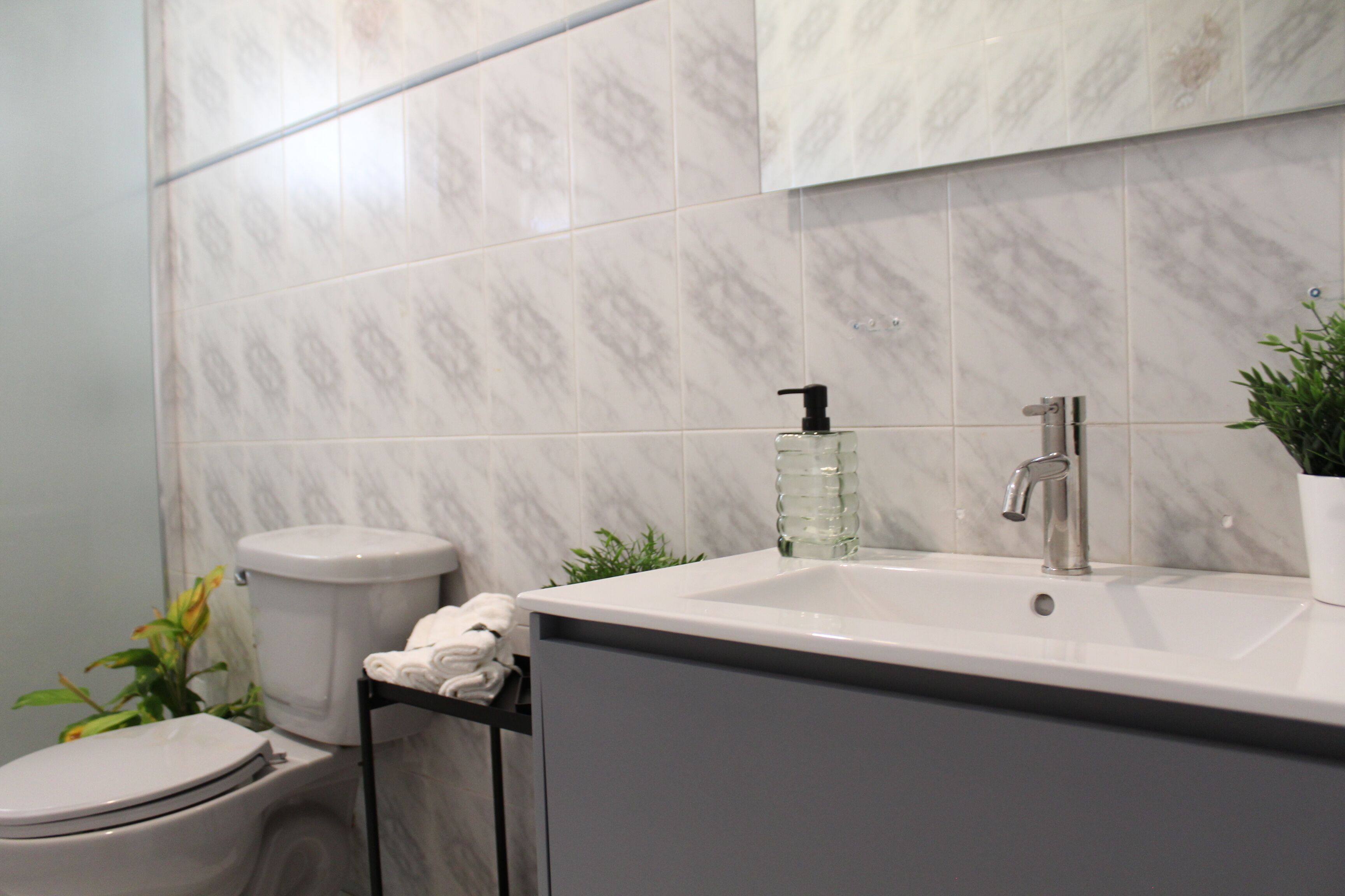 Un baño con inodoro, lavamanos y una planta.